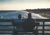 man and woman sitting on bench in front of beach