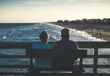 man and woman sitting on bench in front of beach