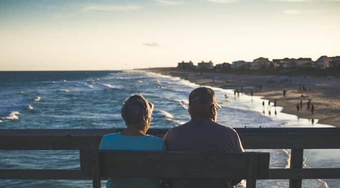 man and woman sitting on bench in front of beach